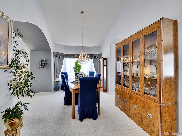 dining space with a chandelier, light colored carpet, and vaulted ceiling