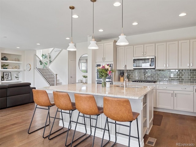 3056 Yale Dr, Broomfield, CO 80023 - kitchen featuring stainless steel appliances, wood finished floors, a breakfast bar, white cabinets, and recessed lighting