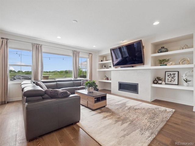3056 Yale Dr, Broomfield, CO 80023 - living room with wood finished floors, plenty of natural light, a tiled fireplace, built in shelves, and recessed lighting