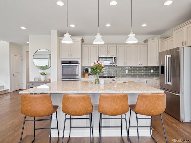 3056 Yale Dr, Broomfield, CO 80023 - kitchen featuring stainless steel appliances, recessed lighting, wood finished floors, a center island with sink, and decorative backsplash