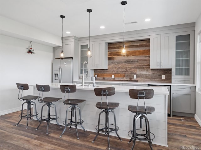 3056 Yale Dr, Broomfield, CO 80023 - kitchen with white refrigerator with ice dispenser, tasteful backsplash, a kitchen island with sink, dark wood finished floors, and recessed lighting