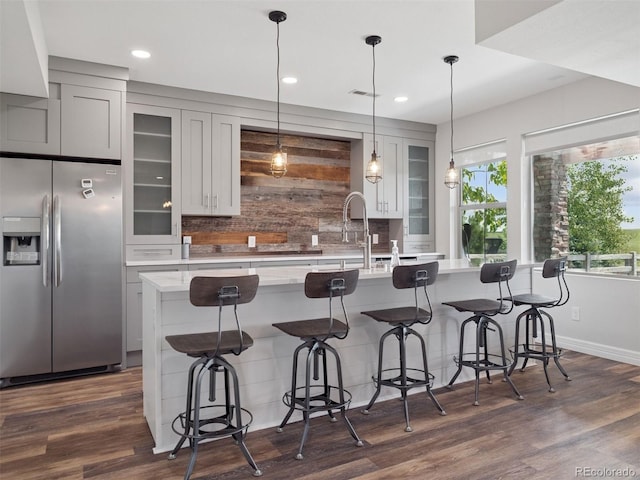 3056 Yale Dr, Broomfield, CO 80023 - kitchen with stainless steel refrigerator with ice dispenser, light countertops, tasteful backsplash, an island with sink, and dark wood finished floors