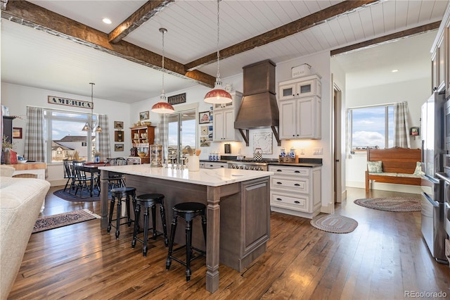 kitchen featuring decorative light fixtures, white cabinetry, a kitchen breakfast bar, custom exhaust hood, and a kitchen island with sink