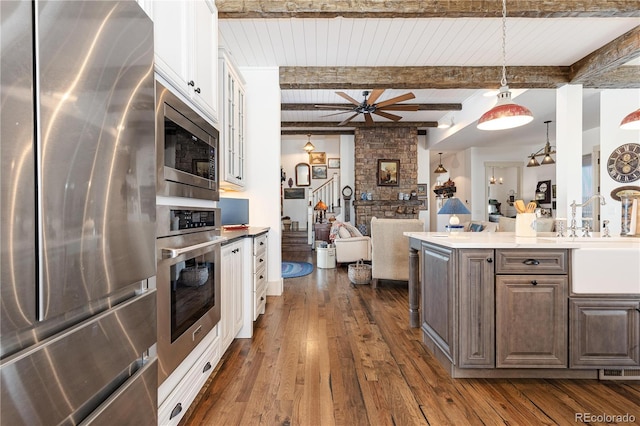 kitchen with pendant lighting, dark wood-type flooring, ceiling fan, dark brown cabinets, and stainless steel appliances