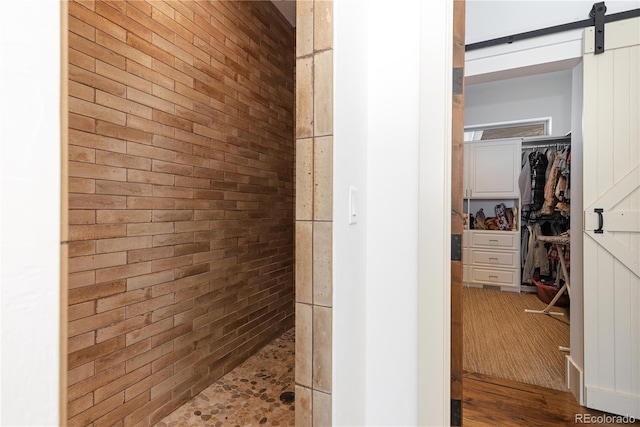 bathroom featuring a tile shower and brick wall