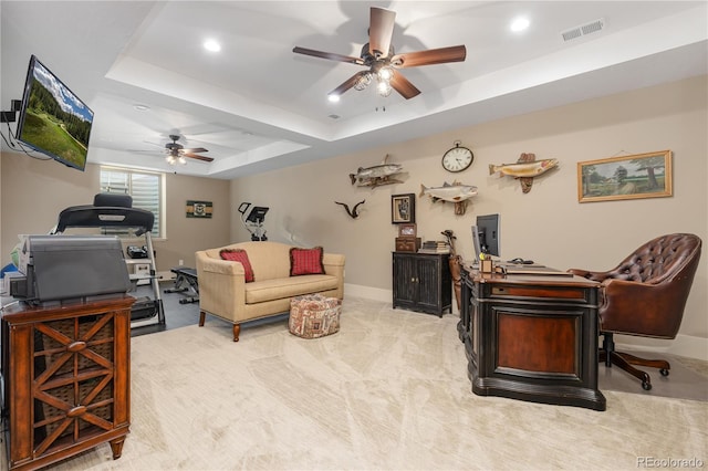 carpeted office featuring ceiling fan and a tray ceiling