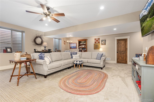 carpeted living room with ceiling fan with notable chandelier