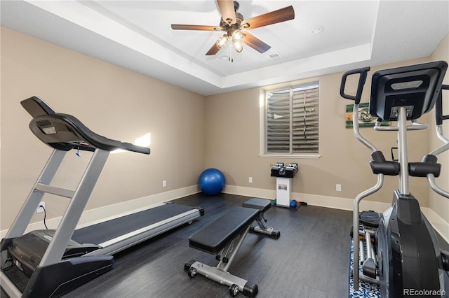 exercise area featuring ceiling fan and a tray ceiling