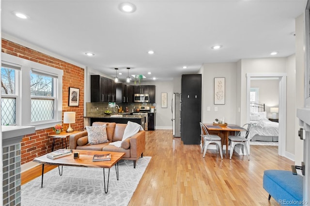 living room with sink, brick wall, and light hardwood / wood-style flooring