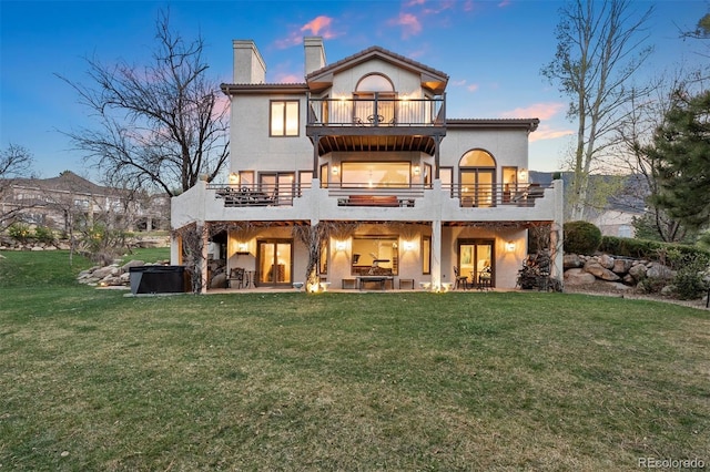 150 Chantrey Ct, Colorado Springs, CO 80906 - back of house at dusk featuring a hot tub, a chimney, a patio area, a balcony, and a lawn