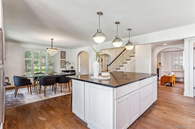 kitchen with white cabinets, pendant lighting, hardwood / wood-style flooring, and a kitchen island