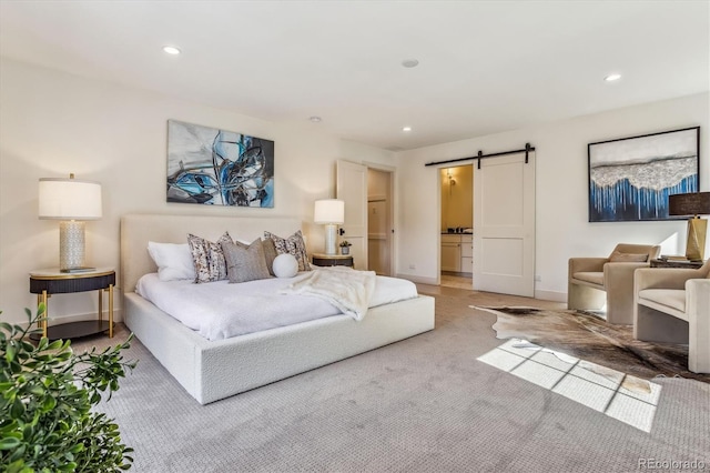 carpeted bedroom with a barn door and ensuite bathroom