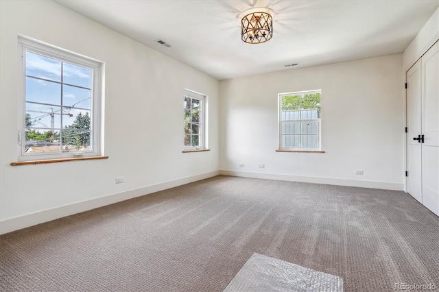 empty room featuring carpet and an inviting chandelier