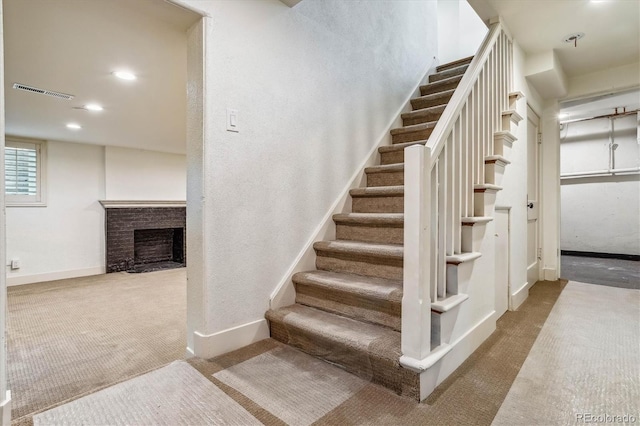 stairway featuring carpet floors and a fireplace