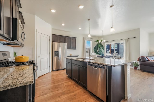 kitchen featuring decorative light fixtures, an island with sink, sink, dark brown cabinetry, and stainless steel appliances