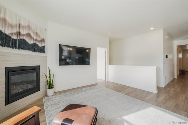 living room featuring a tile fireplace and wood-type flooring