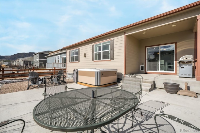 rear view of property with a mountain view, a patio area, and a hot tub