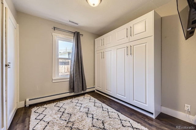 235 W Lehigh Ave, Englewood, CO 80110 - unfurnished bedroom with a baseboard heating unit and dark wood-type flooring