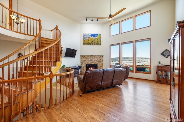 50 Deerwood Dr, Littleton, CO 80127 - living area featuring a ceiling fan, wood finished floors, a fireplace, a high ceiling, and a chandelier