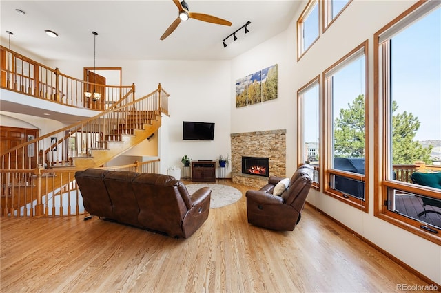 50 Deerwood Dr, Littleton, CO 80127 - living area featuring a towering ceiling, wood finished floors, a ceiling fan, a stone fireplace, and stairs