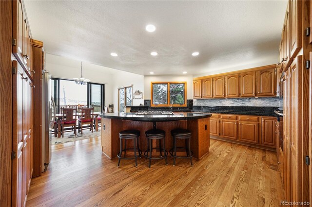 50 Deerwood Dr, Littleton, CO 80127 - kitchen featuring light wood-style floors, a kitchen bar, brown cabinets, recessed lighting, and a center island