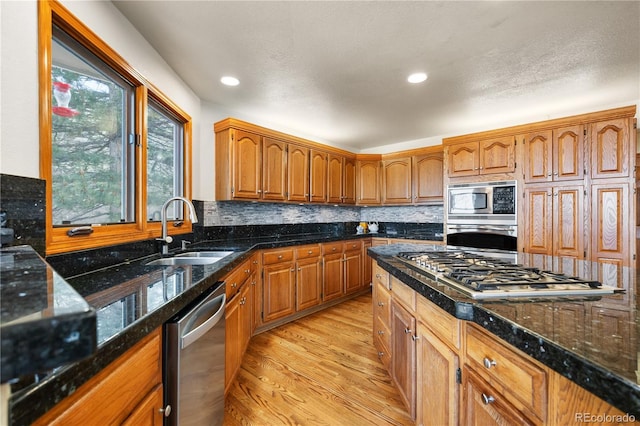 50 Deerwood Dr, Littleton, CO 80127 - kitchen with appliances with stainless steel finishes, a sink, light wood finished floors, backsplash, and brown cabinets