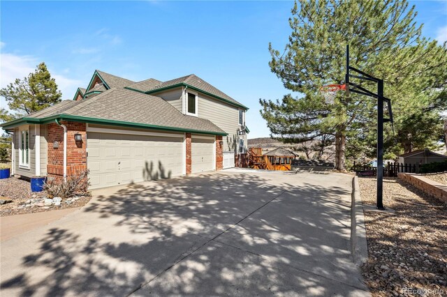 50 Deerwood Dr, Littleton, CO 80127 - view of side of home with brick siding, driveway, roof with shingles, and a garage