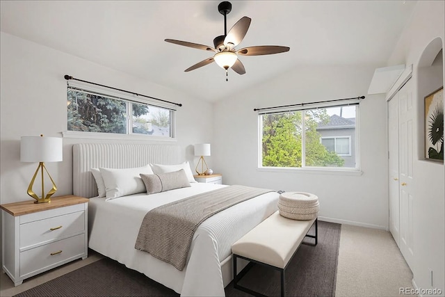 bedroom featuring vaulted ceiling, multiple windows, a closet, baseboards, and dark colored carpet