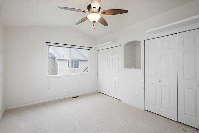 unfurnished bedroom with multiple closets, carpet, baseboards, vaulted ceiling, and a ceiling fan