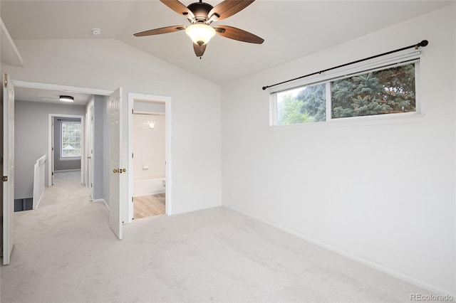 unfurnished bedroom with light carpet, vaulted ceiling, multiple windows, baseboards, and ceiling fan
