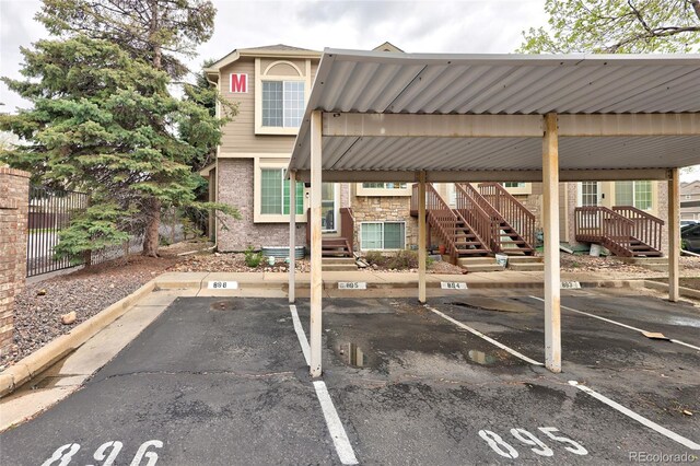 covered parking lot featuring stairs and fence