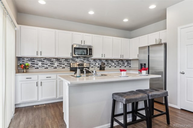 6491 N Danube St, Denver, CO 80249 - kitchen featuring appliances with stainless steel finishes, light countertops, white cabinetry, dark wood finished floors, and recessed lighting