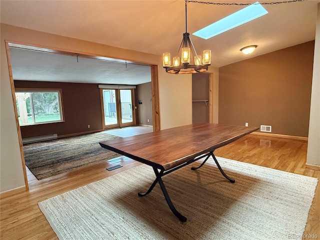 8930 W 55th Ave, Arvada, CO 80002 - unfurnished dining area featuring baseboard heating, light wood-style flooring, a chandelier, and a skylight