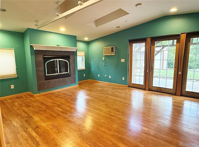 8930 W 55th Ave, Arvada, CO 80002 - unfurnished living room with wood finished floors, an AC wall unit, a fireplace, lofted ceiling, and a skylight