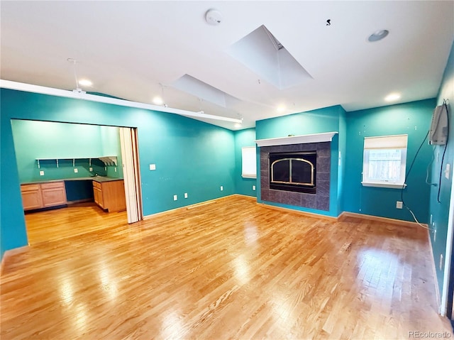 8930 W 55th Ave, Arvada, CO 80002 - unfurnished living room featuring light wood finished floors, a tiled fireplace, a skylight, and recessed lighting
