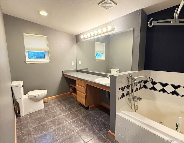 8930 W 55th Ave, Arvada, CO 80002 - bathroom featuring a tub with jets, vanity, marble look tiles, and recessed lighting