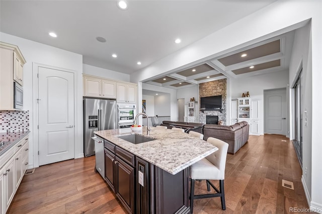23615 E Del Norte Pl, Aurora, CO 80016 - kitchen with stainless steel appliances, cream cabinets, a breakfast bar, light stone countertops, and a kitchen island with sink