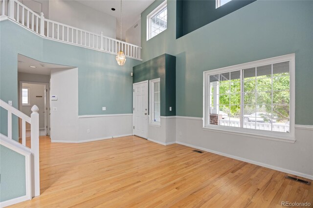18121 E Adriatic, Aurora, CO 80013 - unfurnished living room featuring wood finished floors, a high ceiling, and baseboards