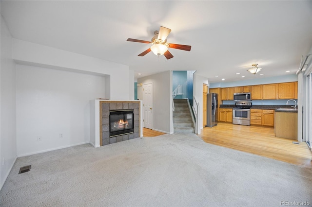 18121 E Adriatic, Aurora, CO 80013 - unfurnished living room with light carpet, stairs, recessed lighting, a ceiling fan, and a fireplace