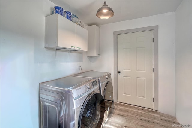 washroom featuring light wood-type flooring, cabinets, and washer and clothes dryer