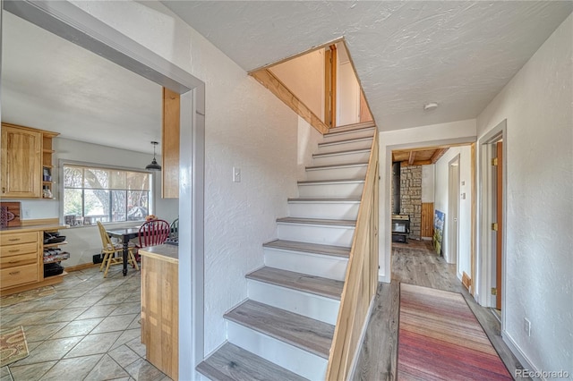 stairs featuring hardwood / wood-style flooring, brick wall, and a wood stove