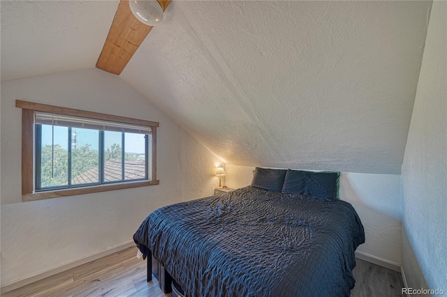 bedroom with light wood-type flooring, a textured ceiling, and lofted ceiling