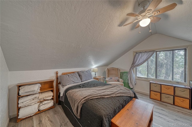 bedroom featuring ceiling fan, vaulted ceiling, light hardwood / wood-style flooring, and a textured ceiling