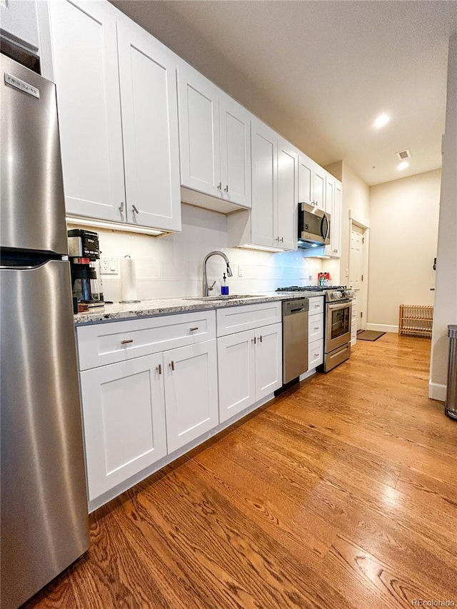 824 Grand Ave Unit 110, Grand Lake, CO 80447 - kitchen featuring appliances with stainless steel finishes, a sink, light wood-type flooring, white cabinetry, and baseboards