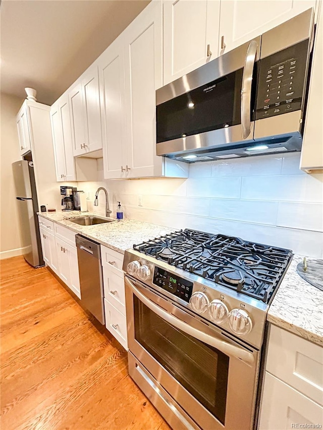 824 Grand Ave Unit 110, Grand Lake, CO 80447 - kitchen featuring stainless steel appliances, a sink, light wood-style flooring, tasteful backsplash, and white cabinets