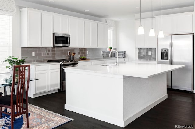 500 176th Ave, Broomfield, CO 80023 - kitchen featuring decorative backsplash, appliances with stainless steel finishes, a sink, dark wood-type flooring, and an island with sink