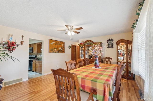 dining area with baseboards, light wood-type flooring, visible vents, and a ceiling fan