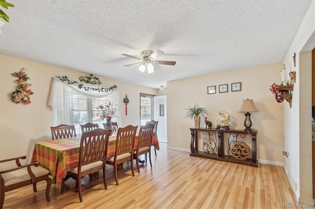 dining space with a textured ceiling, light wood-type flooring, a ceiling fan, and baseboards