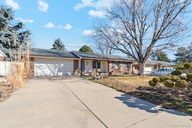 ranch-style home featuring concrete driveway, brick siding, an attached garage, and fence