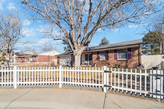 ranch-style house with a fenced front yard, brick siding, driveway, and a garage